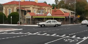 Road with cars on a two-way lanes showing a white car turning left.