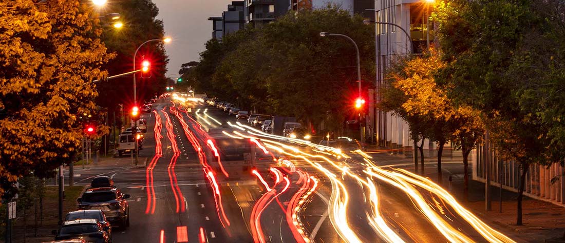 A busy night scene of cars on the road in a city setting